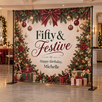 Fifty and Festive Christmas birthday backdrop with a red bow, ornaments, evergreen border and gifts.