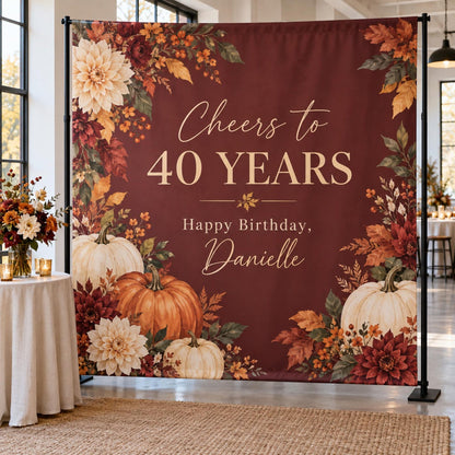 Burgundy Cheers to 40 Years birthday backdrop with pumpkins and autumn flowers.