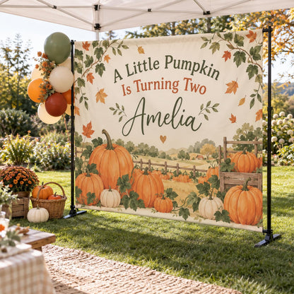 A Little Pumpkin Is Turning Two backdrop with personalized name, pumpkin patch artwork and balloons.