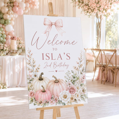 Isla's second birthday welcome sign with a pink bow, pastel pumpkins and flowers.
