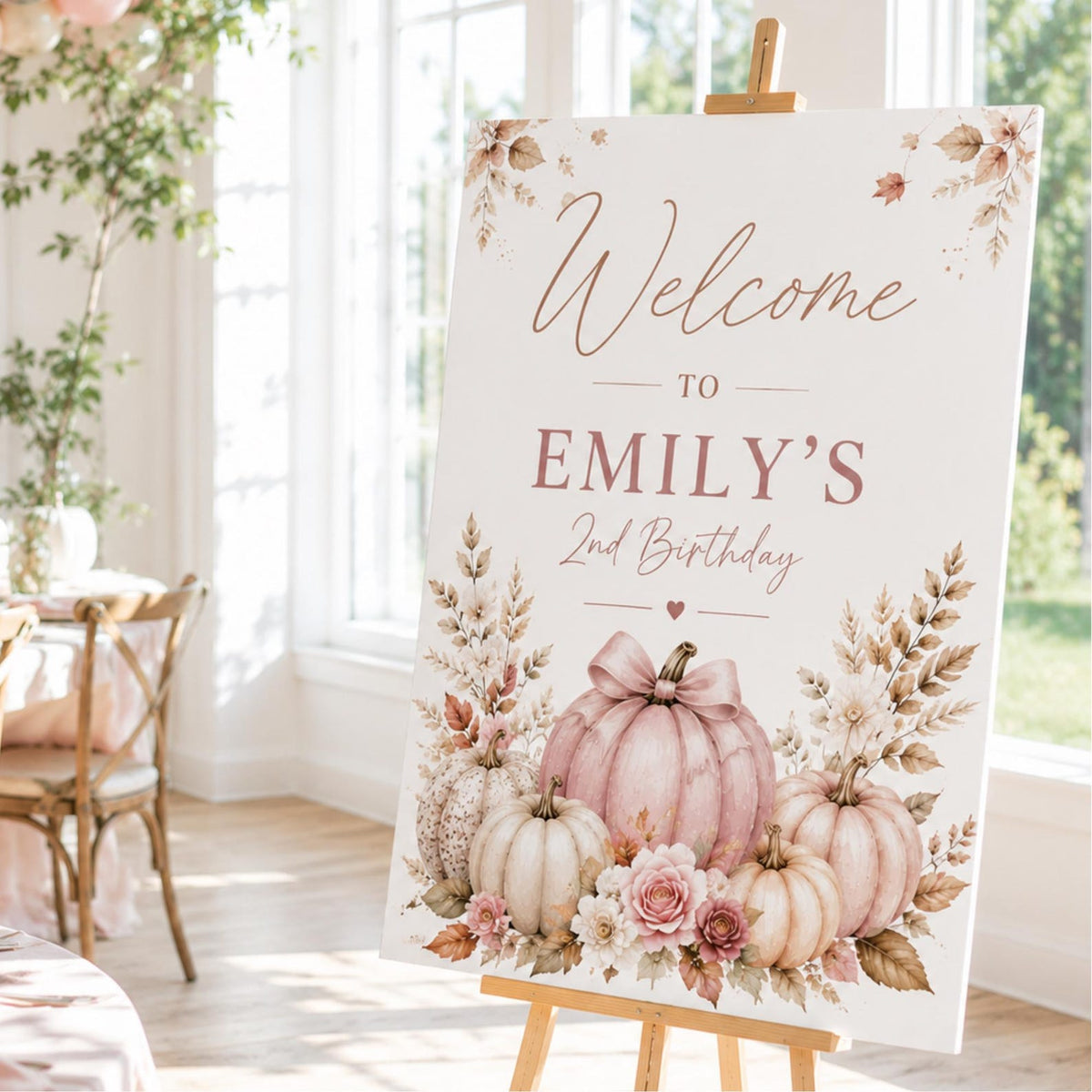 Emily's second birthday welcome sign with pink pumpkins, pale flowers and autumn foliage.